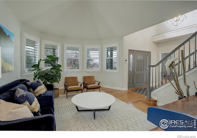 living room with stairs, wood finished floors, a wealth of natural light, and baseboards