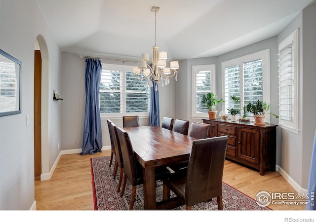 dining room featuring plenty of natural light, light wood-style flooring, and arched walkways