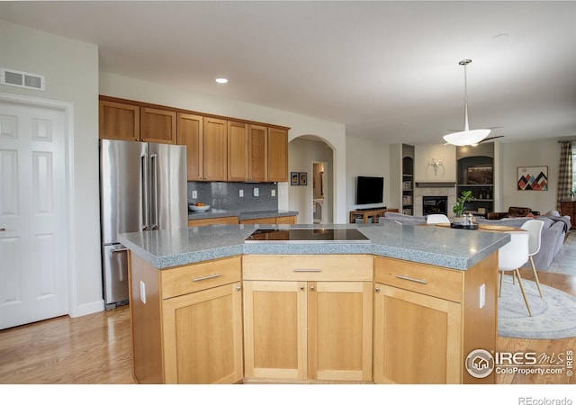 kitchen featuring visible vents, decorative backsplash, a center island, freestanding refrigerator, and a fireplace