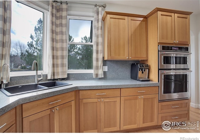 kitchen featuring double oven, a sink, and decorative backsplash