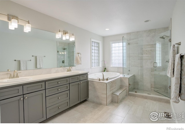 full bathroom with double vanity, a garden tub, a shower stall, and a sink