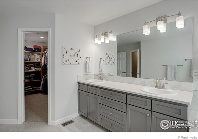 bathroom with double vanity, a spacious closet, a sink, and tile patterned floors