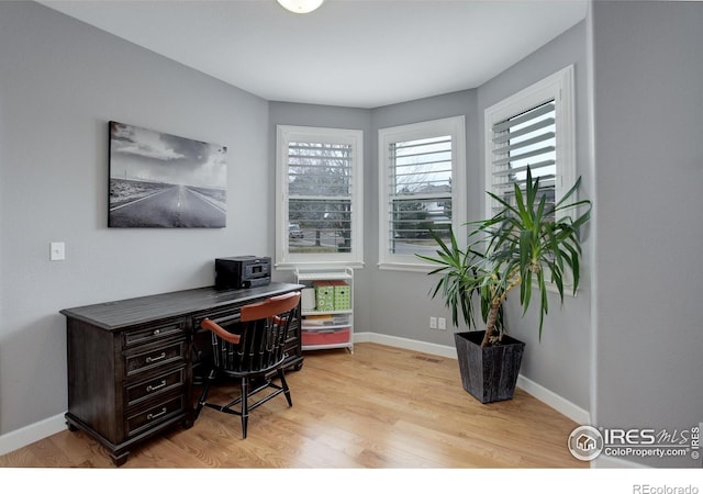 home office with light wood-type flooring and baseboards