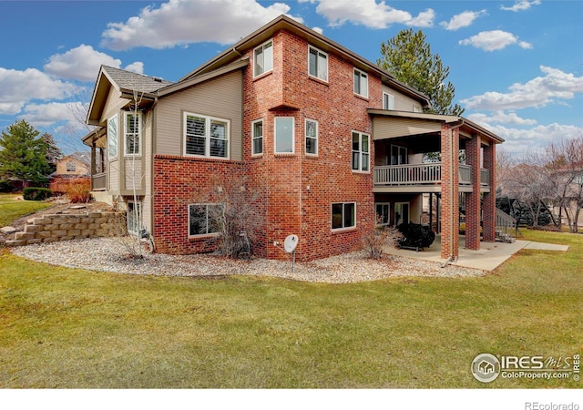 exterior space with a deck, a patio, brick siding, a lawn, and stairway