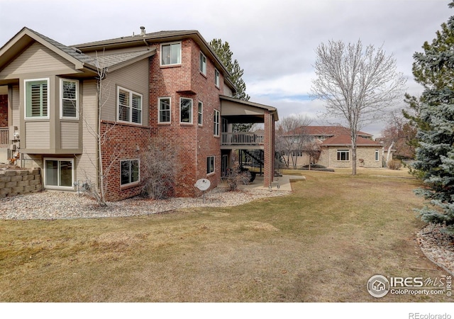 rear view of house featuring stairs, a yard, and brick siding