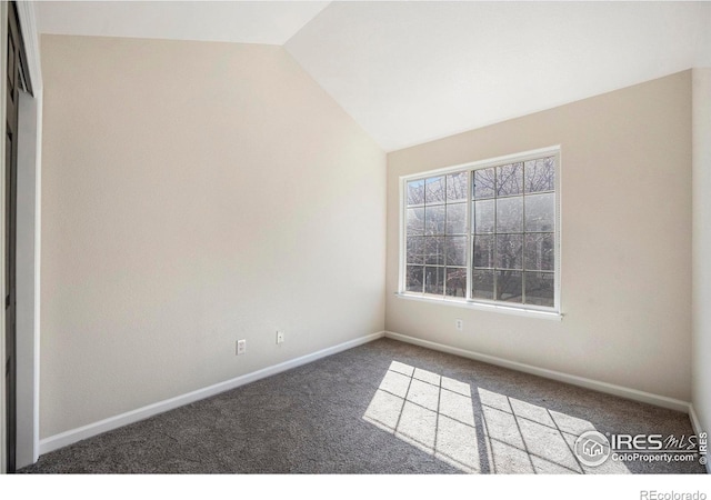 empty room featuring lofted ceiling, baseboards, and carpet floors