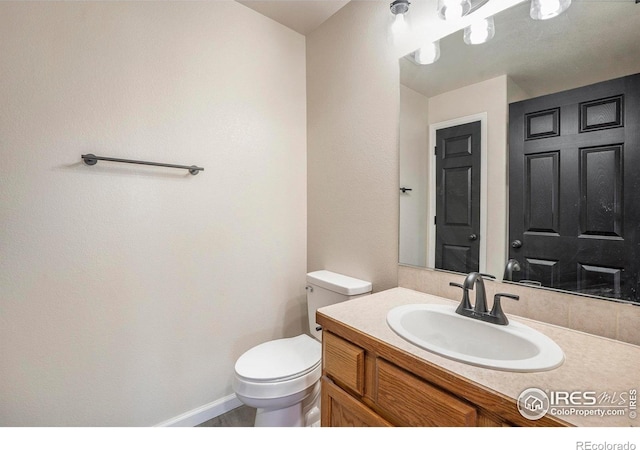 bathroom featuring vanity, toilet, and baseboards