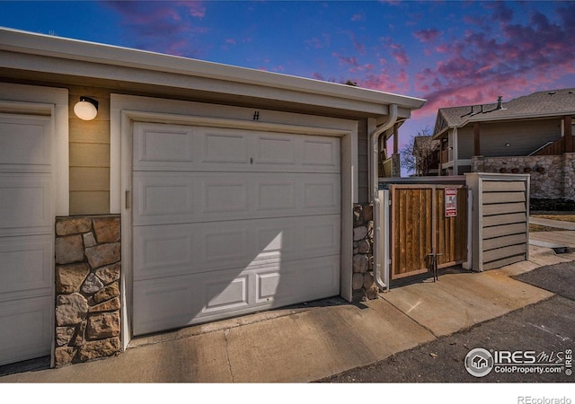 garage at dusk featuring a gate