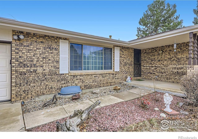 property entrance featuring an attached garage and brick siding