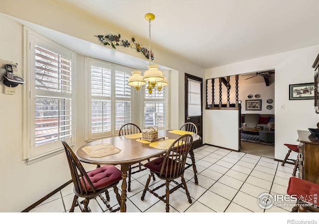 dining room with ceiling fan with notable chandelier, baseboards, and light tile patterned floors