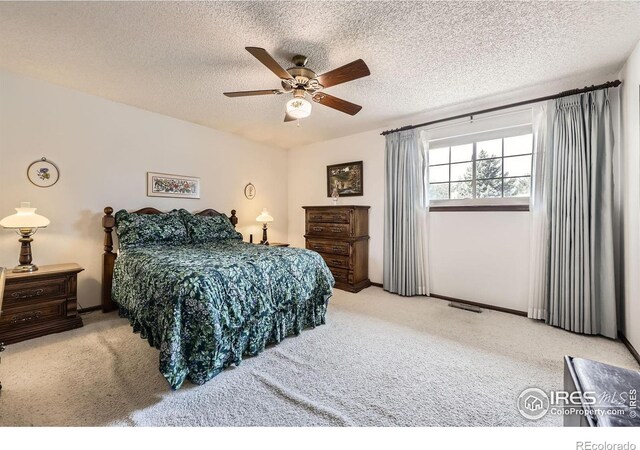 carpeted bedroom featuring a textured ceiling, visible vents, and a ceiling fan