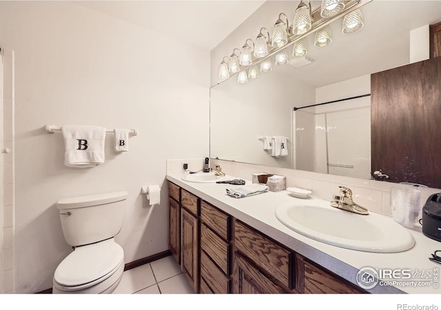 full bathroom featuring toilet, double vanity, a sink, and tile patterned floors