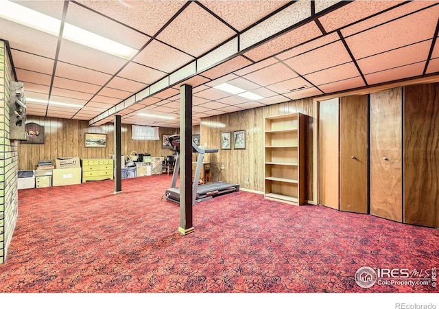 below grade area with carpet floors, a paneled ceiling, and wooden walls