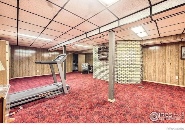 workout room featuring a paneled ceiling, wood walls, and carpet flooring