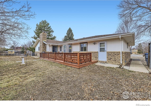 rear view of house with a chimney, fence, a deck, cooling unit, and brick siding