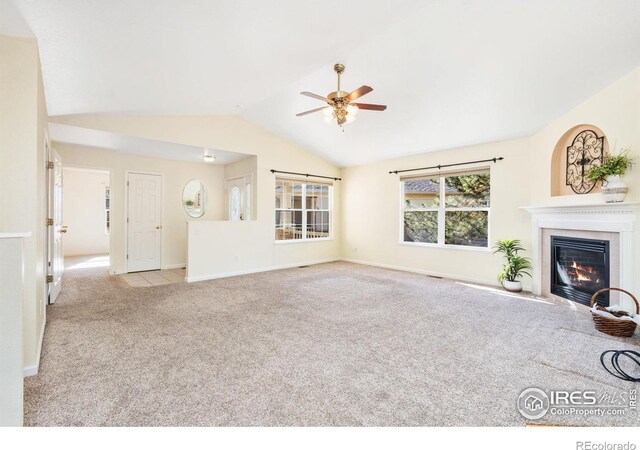 unfurnished living room featuring carpet, lofted ceiling, a glass covered fireplace, ceiling fan, and baseboards