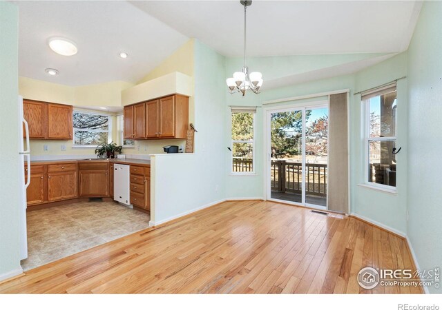 kitchen with hanging light fixtures, light wood-style flooring, vaulted ceiling, and dishwasher