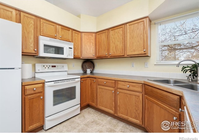 kitchen featuring white appliances, brown cabinets, and a sink