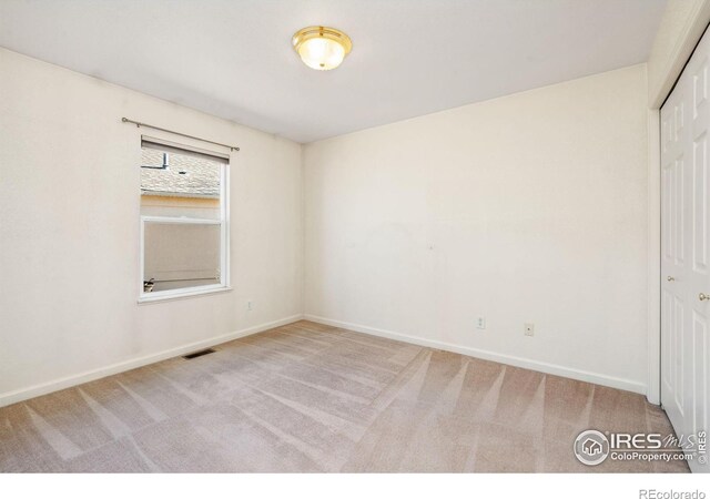 carpeted spare room featuring baseboards and visible vents