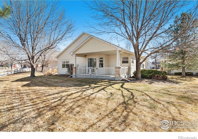 view of front of house with fence, a front lawn, a porch, and stucco siding