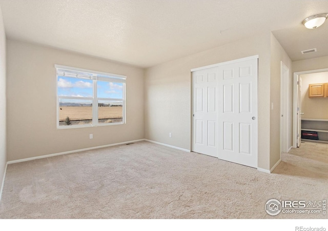 unfurnished bedroom featuring a closet, visible vents, baseboards, and carpet floors