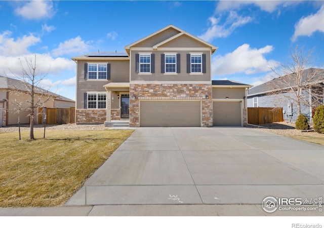 view of front of property featuring fence, driveway, solar panels, a front lawn, and stone siding