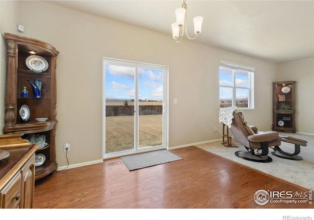 sitting room with baseboards, wood finished floors, visible vents, and a chandelier