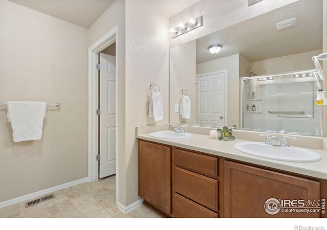 bathroom with a sink, visible vents, a stall shower, and double vanity