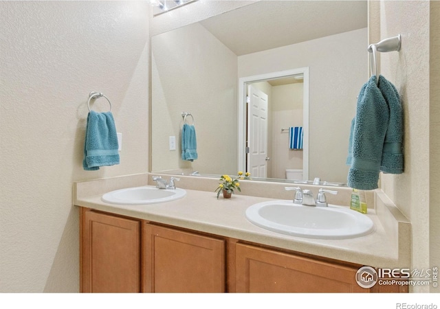 bathroom featuring double vanity, toilet, and a sink