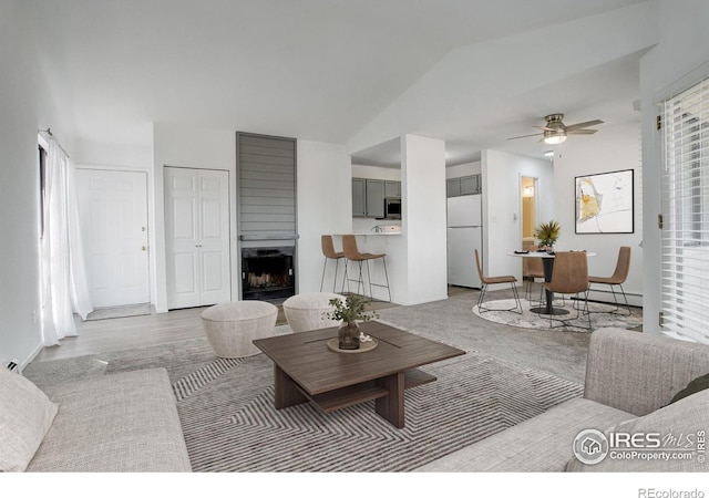 carpeted living room featuring lofted ceiling, a baseboard radiator, a fireplace, and ceiling fan