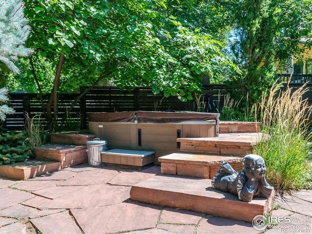 view of patio featuring fence and a hot tub