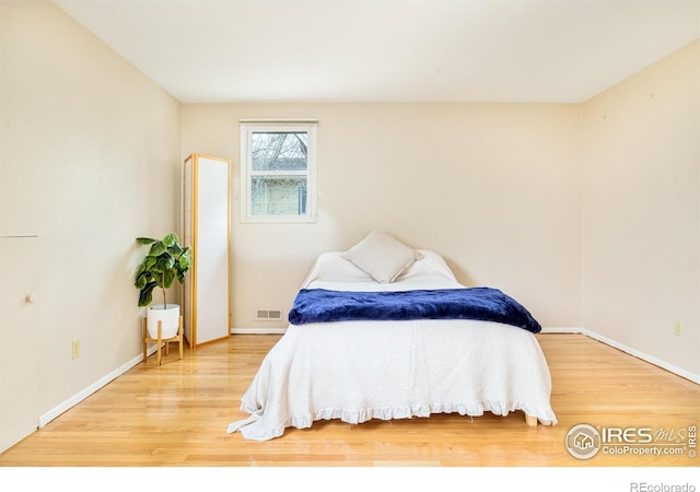 bedroom with wood finished floors, visible vents, and baseboards