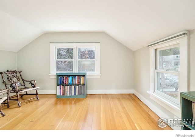 sitting room featuring lofted ceiling, wood-type flooring, and baseboards