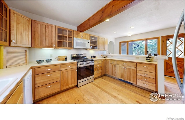 kitchen with a peninsula, white appliances, beam ceiling, light wood finished floors, and glass insert cabinets