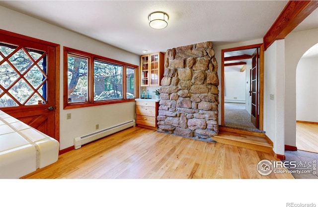 entryway with light wood finished floors, arched walkways, baseboard heating, and a wealth of natural light