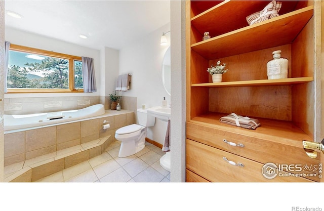 bathroom featuring a relaxing tiled tub, toilet, and tile patterned floors