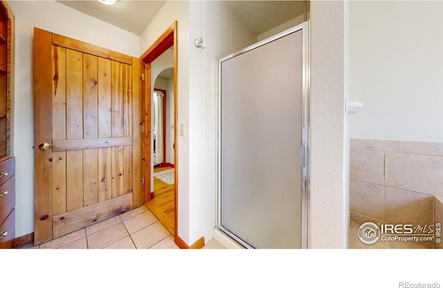 full bathroom featuring a shower stall and tile patterned flooring