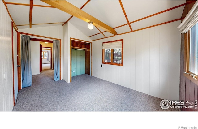 unfurnished bedroom featuring carpet floors, a closet, multiple windows, and lofted ceiling with beams