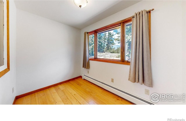 unfurnished room featuring light wood-type flooring, baseboards, and baseboard heating