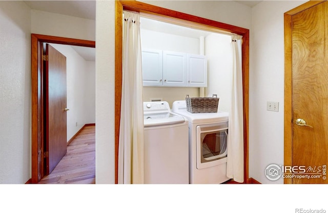 clothes washing area featuring cabinet space, independent washer and dryer, and light wood finished floors