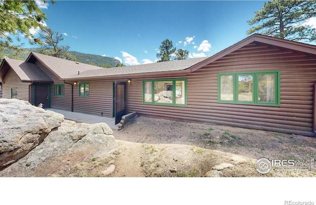 view of front of house featuring log veneer siding and roof with shingles