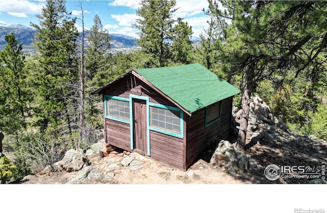 view of outdoor structure featuring an outbuilding, a mountain view, and a view of trees