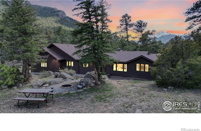 view of front of house with log veneer siding, a mountain view, and a fire pit