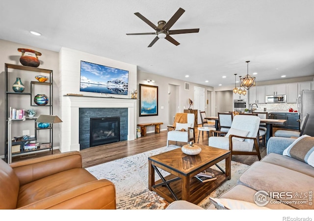 living room featuring a glass covered fireplace, visible vents, recessed lighting, and wood finished floors