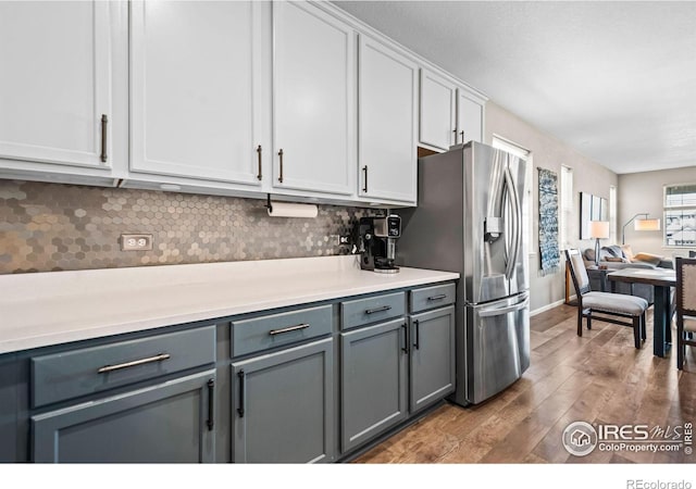 kitchen featuring tasteful backsplash, gray cabinets, light countertops, wood finished floors, and stainless steel fridge