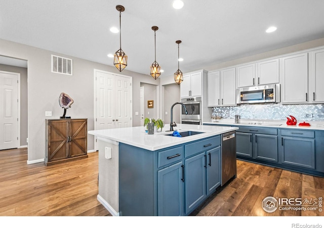 kitchen featuring visible vents, appliances with stainless steel finishes, a sink, wood finished floors, and blue cabinets