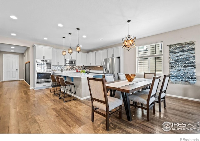 dining room featuring light wood-type flooring, baseboards, a chandelier, and recessed lighting