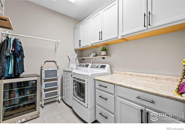 laundry room with cabinet space, beverage cooler, light tile patterned floors, and separate washer and dryer