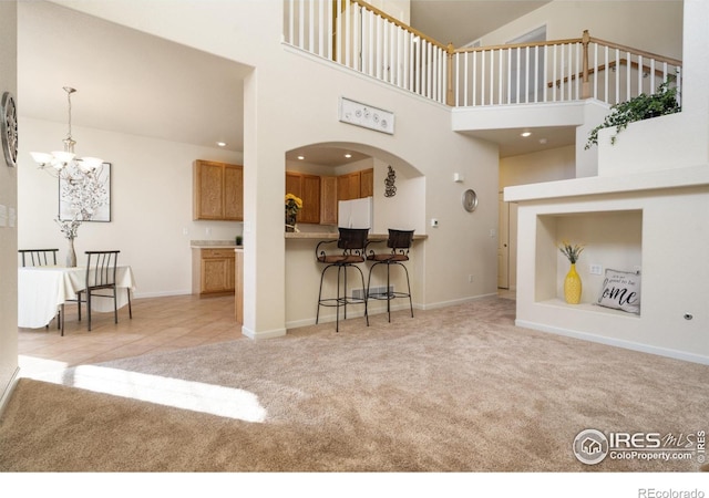 carpeted living area featuring arched walkways, recessed lighting, a notable chandelier, a towering ceiling, and baseboards