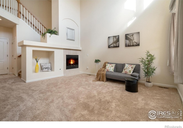 sitting room with a high ceiling, a fireplace, carpet flooring, and baseboards